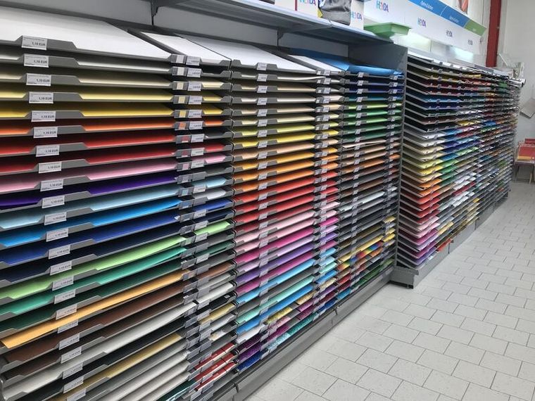 Regalwand mit flach sortierten Bastelkartonbögen in vielen Farben und Farbabstufungen