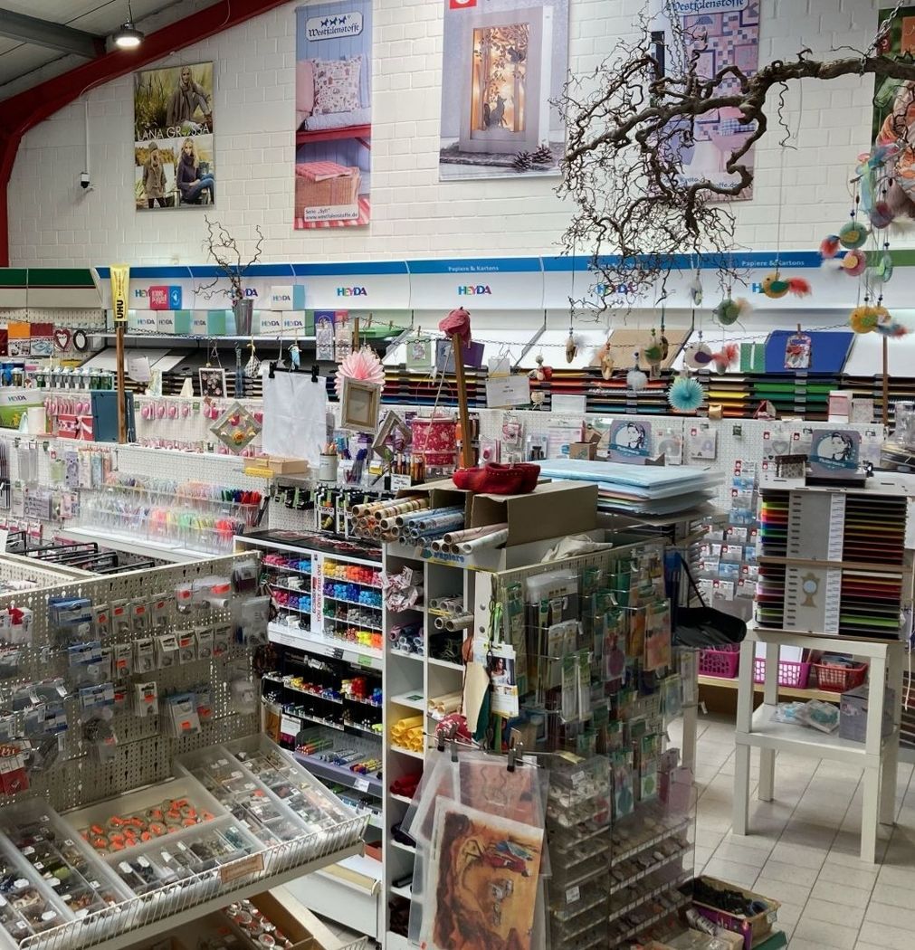 Innenansicht eines Bastelgeschäfts mit Regalen voller Papier, Stempel, Farben, Dekorationen und Bastelmaterialien
